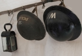 WWII helmets and lantern hanging on wall.